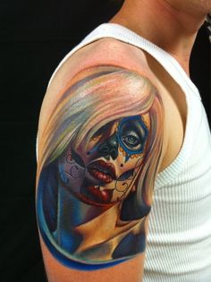 a woman's shoulder with a colorful tattoo on her face and the image of a skull