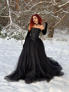 a woman with red hair wearing a black dress in the snow