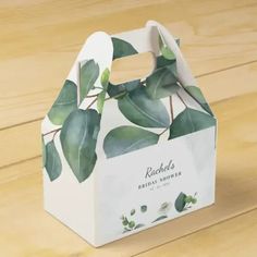 a white paper bag with green leaves on the front and bottom, sitting on a wooden surface