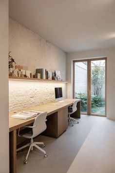 a home office with two desks and a large glass door leading to the outside