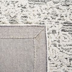 an area rug with a square design on the top and bottom corner, in grey tones