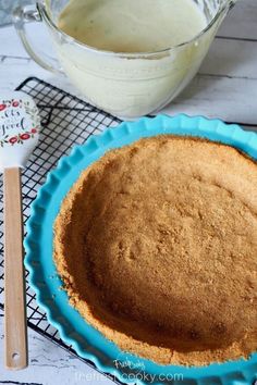 a pie sitting on top of a blue plate next to a glass bowl and wooden spoon