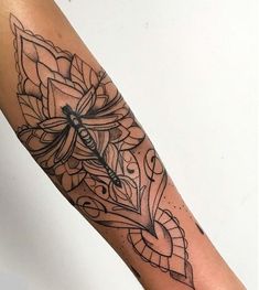 a woman's arm with a dragonfly on it and flowers in the middle