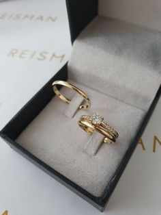 two gold rings sitting in a box on top of a table