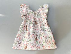 "New... Spring dress with vintage inspired Bunny Rabbits!  This charming little flutter sleeve dress is handmade in an off-white cotton fabric with bunny rabbits in a flower garden. The rabbits are brown or gray and white, with pink shading at the ears, and the garden like background is lush with flowers, leaves and branches, in shades of pink, green and brown. For infant and toddlers, I have added matching bloomers to complete the outfit :)  No bloomers for dress sizes 2T through 6... and sizes 12m and 18m are available with the dress only. Such a sweet little dress would be perfect for her first Easter... and it would make a charming \"coming home\" outfit... or the perfect dress for your bunny loving young lady! This dress gathers at the neckline on elastic to form a modest oval scoop n White Dress For Easter Garden Party, White Dress With Ruffle Hem And Butterfly Sleeves, White Ruffled Dresses With Butterfly Sleeves, White Butterfly Sleeve Dresses With Ruffles, White Dresses With Ruffles And Butterfly Sleeves, Easter Dresses With Ruffles And Short Sleeves, 4t Dress, Rabbit Dress, Cotton Frocks