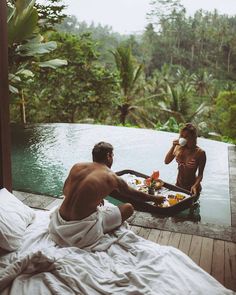 a man and woman sitting on a bed next to a pool