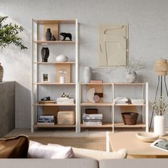 a living room filled with furniture and a book shelf next to a couch in front of a window