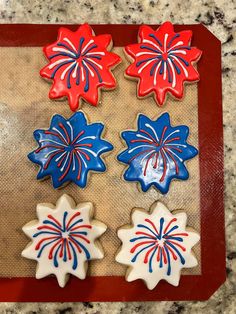 red, white and blue decorated cookies sitting on top of a cookie sheet in the shape of flowers