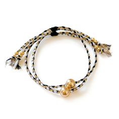 two bracelets with gold beads and black and white braided cord on a white background