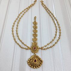 *PRODUCT DETAIL* * Material: Brass * Plating: Gold Plated * Stone: Semi Precious Ruby. *DIMENSIONS * * Weight: 30 gm, One Side Length: 7.5 Inches, Width: 1.2 Inches, Top Chain Length: 3.6 Inches * Pendant Length: 1.2 Inches, Width: 1.3 Inches. *ABOUT PRODUCT* * Beautiful 22K Antique Gold Plated Matha Matti in High Quality. * Style Tip : Wear it with Your Indian Attire to Complete the Indian Look. *DISCLAIMER* * Product & color may slightly vary due to photographic lighting sources or your screen Matha Patti Bridal South Indian, Matha Patti Gold Jewellery, Matha Patti Bridal Gold, South Indian Matha Patti, Matha Patti Bridal, Sheesh Patti, Gold Simple Necklace, Gold Nath, Head Jewellery