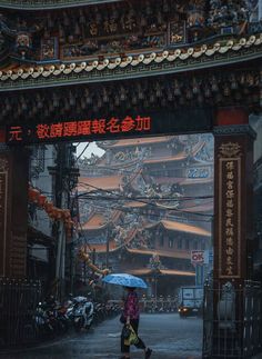 a woman with an umbrella walks under the chinese arch