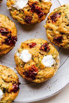 several muffins on a plate with cream cheese and cranberry toppings