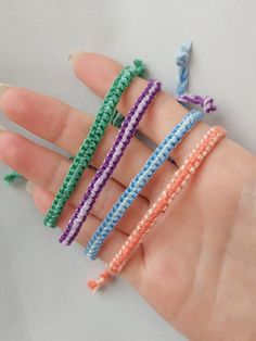 four different colored bracelets are held in someone's hand with their fingers together