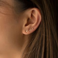 a close up of a person's ear with three piercings on it,