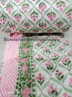 pink flowers and green leaves are on the side of a white quilted bed spread