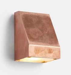 a light that is on the wall in front of a white background with a wooden block