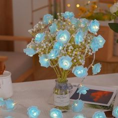 a vase filled with blue roses sitting on top of a table next to a book