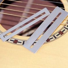 three guitar picks resting on top of an acoustic guitar's fret cover and neck