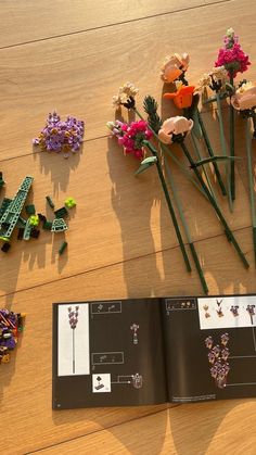 an open book on a table with flowers and legos laying around it in the shape of letters