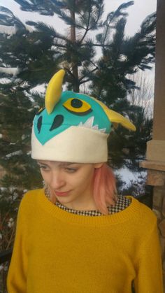 a young woman wearing a knitted hat with a monster head on top of it