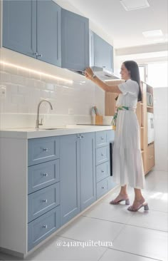 a woman in a white dress is cleaning the kitchen counter top with a sprayer