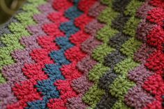 a crocheted blanket that is laying on the ground with it's edges folded down