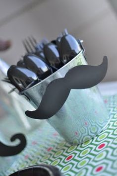 a cup filled with silverware and a fake moustache on top of it