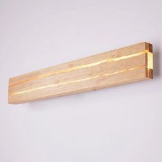 a wooden light fixture on the wall with dim lighting coming from it's side