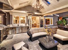 an outdoor kitchen and living room are featured in this photo, while the patio is lit up with chandeliers