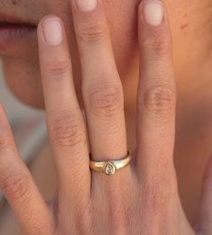 a close up of a person with a ring on their finger and the other hand near her face