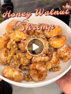 a white bowl filled with honey walnuts on top of a table next to a sign