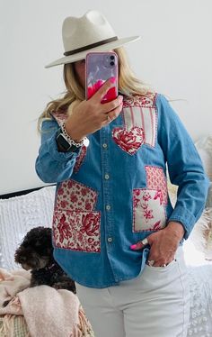 a woman taking a selfie while wearing a hat and denim shirt with patches on it