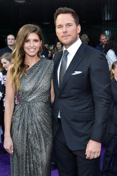 a man and woman standing next to each other on a purple carpet at an event