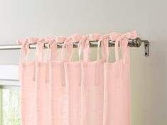 a pink curtain hanging on the side of a window