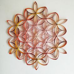 a circular sculpture made out of colored paper on a white wall in the shape of a flower