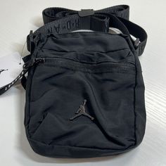 Nwt. Jordan Black Crossbody Sackpack Casual Shoulder Bag For Streetwear, Casual Streetwear Shoulder Bag, Streetwear Crossbody Shoulder Bag With Zipper Closure, Black Nylon Bags With Zipper Closure, Black School Bag With Zipper Pocket, Streetwear Shoulder Bag With Pockets, Black Satchel Backpack With Mobile Phone Bag, Black Shoulder Bag With Zipper For Streetwear, Rectangular Bags With Zipper Pocket For Streetwear