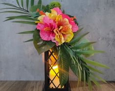 a vase with flowers and candles on a wooden table in front of a concrete wall