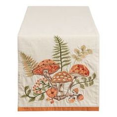 an embroidered table runner with mushrooms and fern leaves on white linen, featuring orange trim