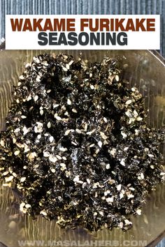 a glass bowl filled with seaweed on top of a wooden table next to a sign that reads wakame furikake seasoning