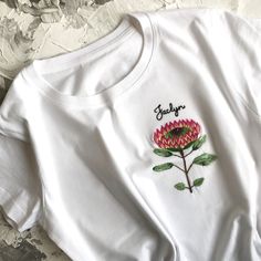 Botanical embroidery unusual women's t-shirt. This white t shirt has been embroidered by hand with a Protea flower on the pocket place. Name can be easily customized! The cute protea embroidery adds some flair and a handcrafted touch to a plain tee. The quality of the embroidery and t-shirt is superior, I guarantee! ;) If for some reason you will not be happy with you t-shirt (but you definitely will!) I will make full refund as I love my customers! DETAILS: All embroidery is done by hand in 100 Protea Embroidery, King Protea Flower, Botanical Embroidery, Custom Crewneck Sweatshirts, King Protea, Protea Flower, Tshirt Custom, Print Ideas, Dog Sweatshirt