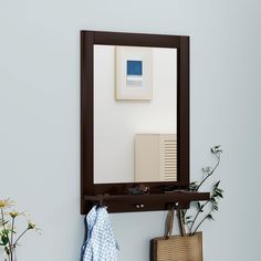 there is a mirror on the wall above a shelf with a towel and other items