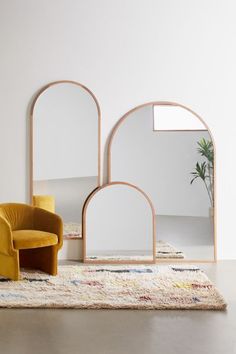 two chairs and a mirror on a rug in front of a wall with an arch