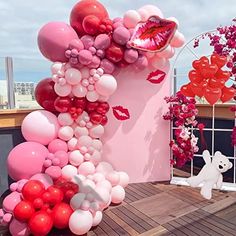 a bunch of balloons that are on the side of a building with pink and red decorations