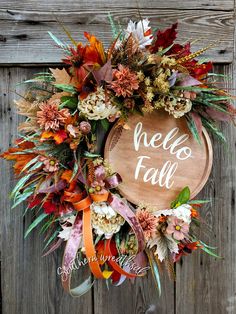 a wreath with the words hello fall written on it and flowers in front of an old wooden door