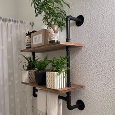 two shelves with plants and books on them in front of a curtained bathroom window