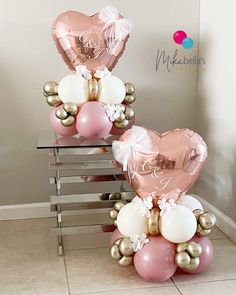 two heart shaped balloons sitting on top of each other in front of a glass table