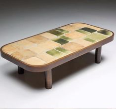 a coffee table with green and yellow tiles on the top, sitting in front of a white background