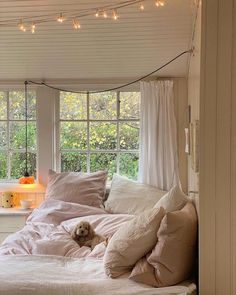 a dog laying on top of a bed in a room with lights strung above it