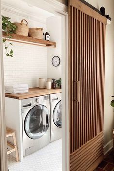 a washer and dryer sitting in a room next to a wooden shelf filled with towels