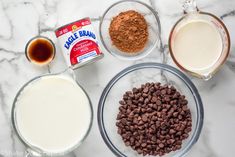 ingredients to make chocolate chip cookies laid out on a marble counter top, including milk and cocoa